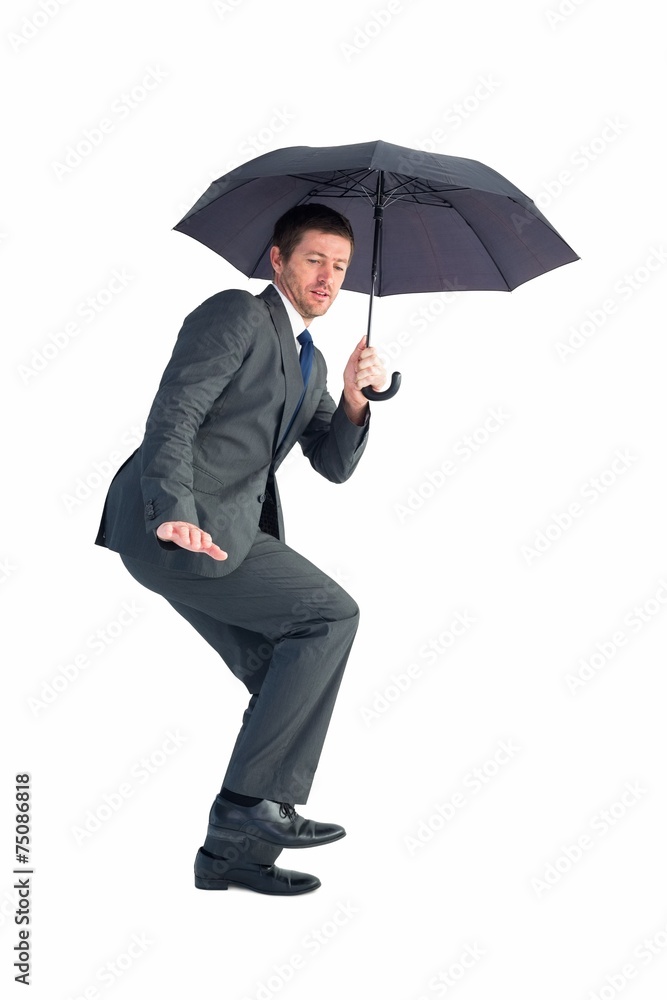 Businessman sheltering under black umbrella Businessman sheltering under black umbrella