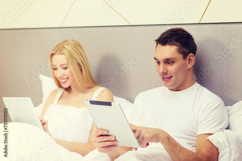 smiling couple in bed with tablet pc computers © Syda Productions