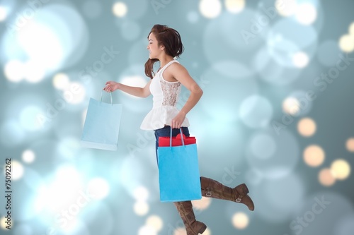 Composite image of happy brunette leaping with shopping bags