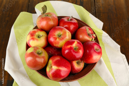 Bowl of red apples with napkin on wooden table background