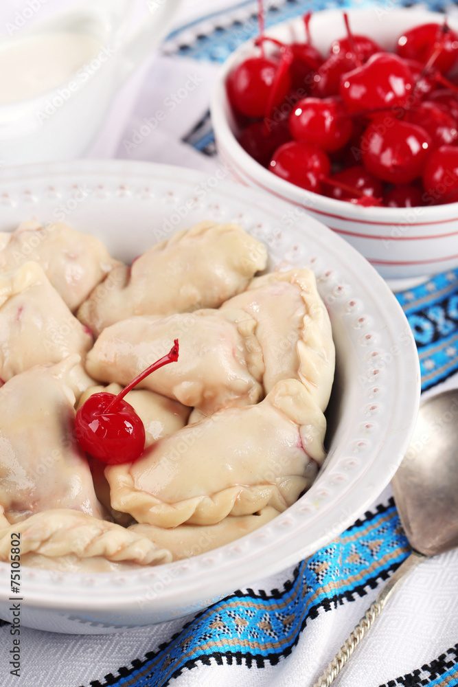 Vareniki with cherry in bowl on tablecloth close-up Vareniki with cherry in bowl on tablecloth close-up