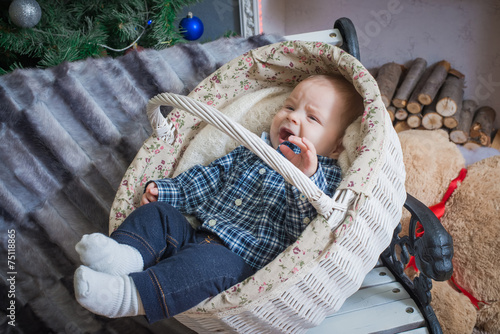 Baby lying in a basket. Christmas tree in the background