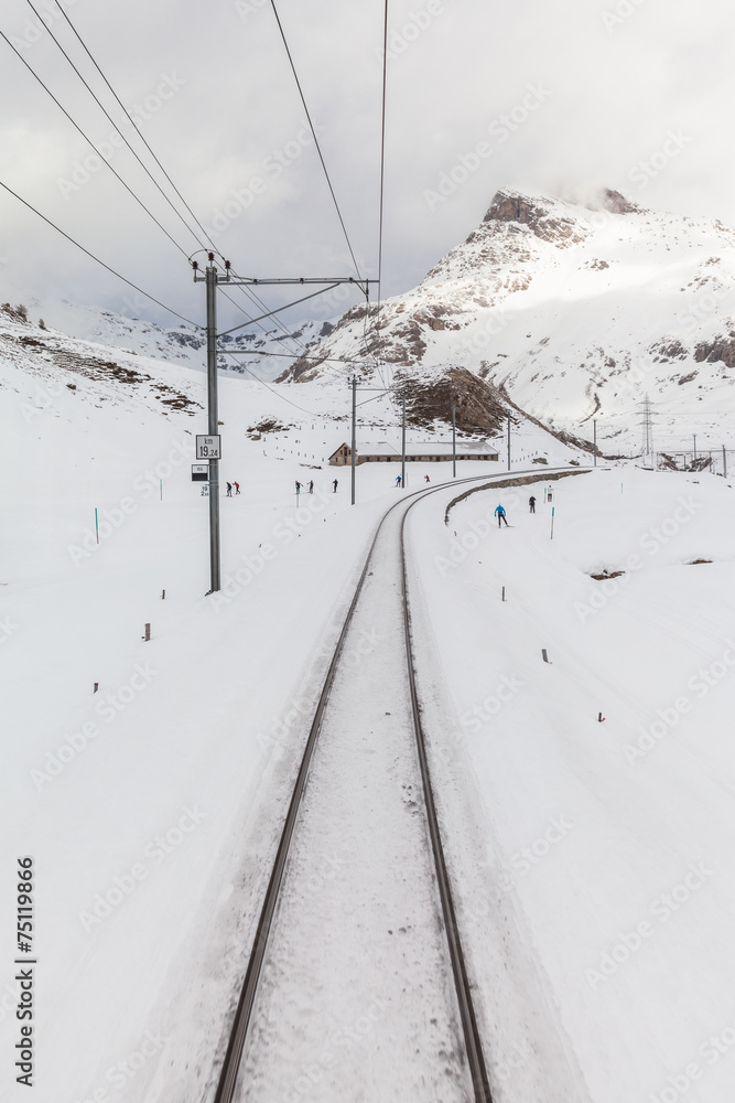 People skiing along the tracks of Bernina Express People skiing along the tracks of Bernina Express