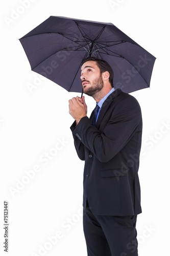 Businesswoman in suit holding umbrella while looking up