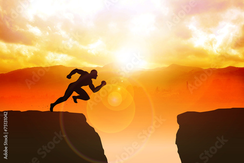 Silhouette of a male figure sprinting to jump the ravine