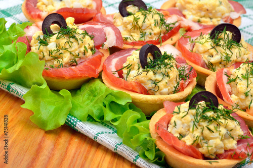 Holiday tartlets stuffed with eggs, ham, olives and green lettuc photo