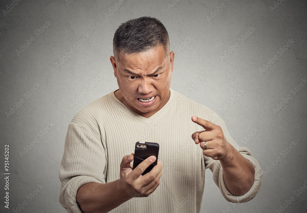 angry middle aged man while on mobile, pointing at smart phone angry middle aged man while on mobile, pointing at smart phone