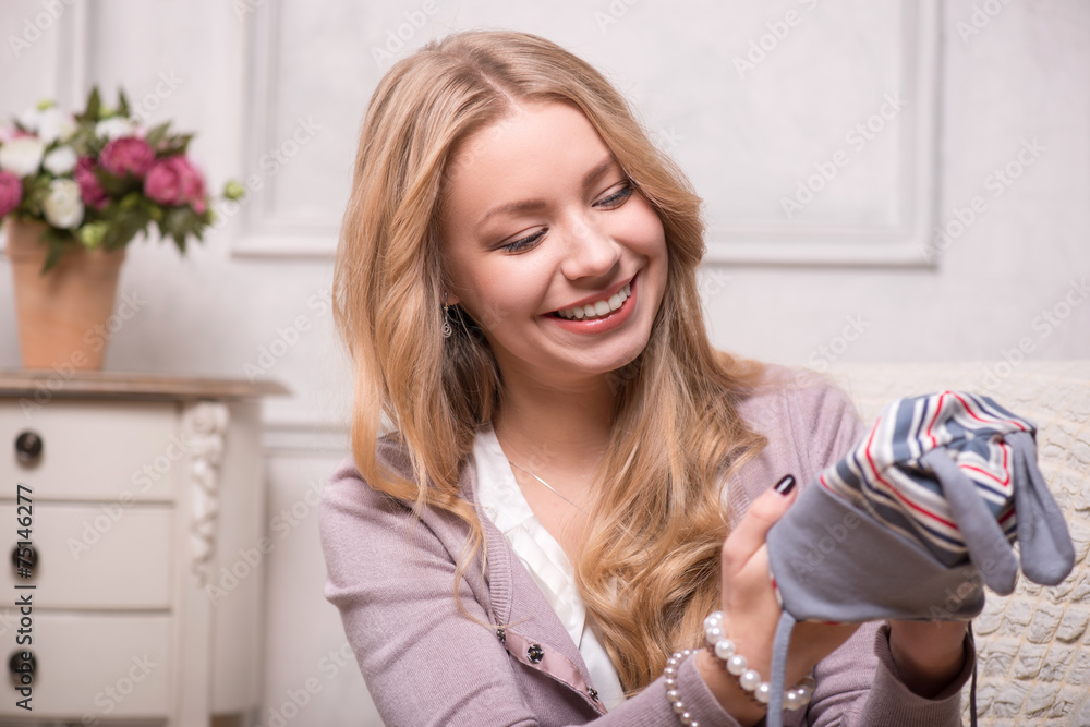 Young attractive woman holding baby hat , interior shot Young attractive woman holding baby hat , interior shot
