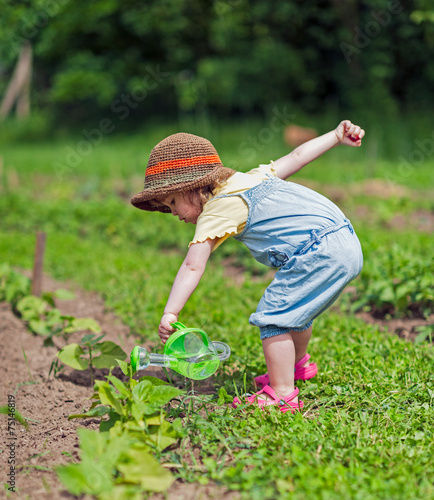 Kind gießt Gemüsebeet
