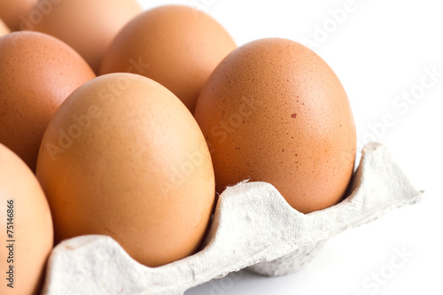Corner of a tray of eggs on white background.