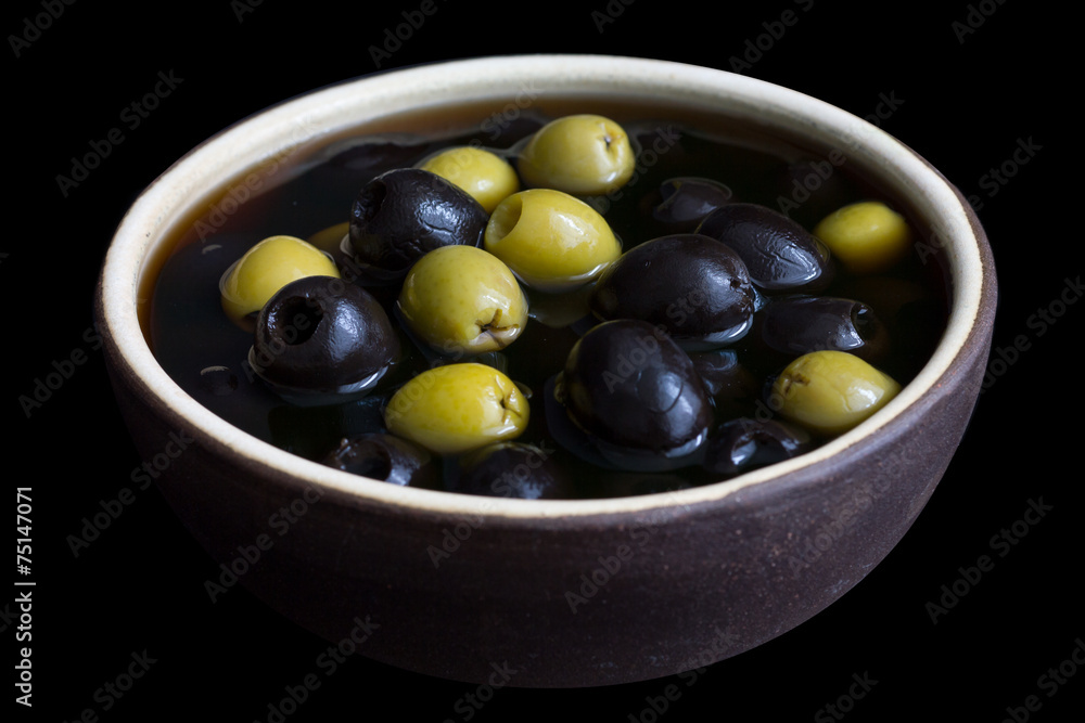 Ceramic rustic bowl of black and green olives on black surface. Ceramic rustic bowl of black and green olives on black surface.