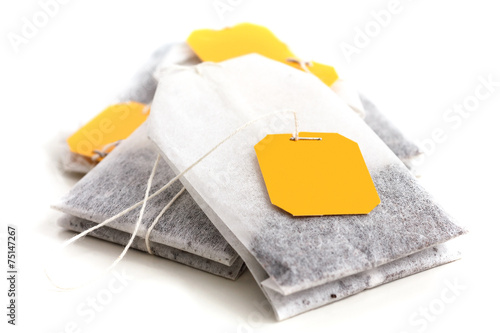Tagged teabags with string on white surface.