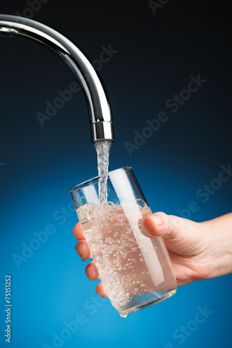 hand pouring a glass of water from filter tap