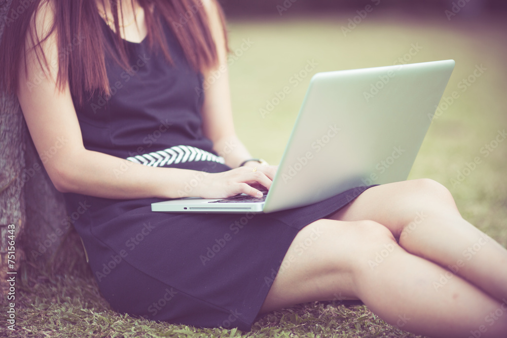 Naklejka premium Beautiful young woman using laptop in park