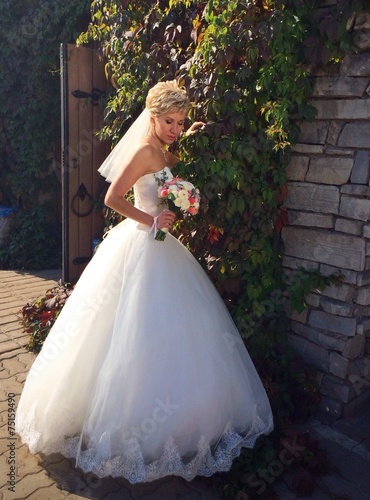 bride posing near stone wall with vine