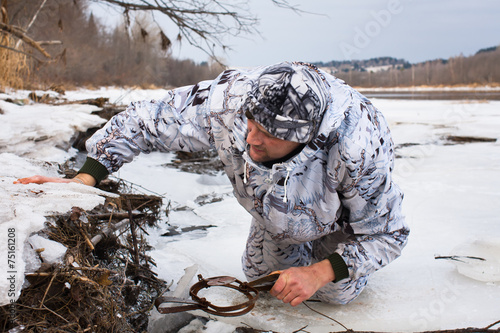 hunter putting a leghold trap for beaver photo