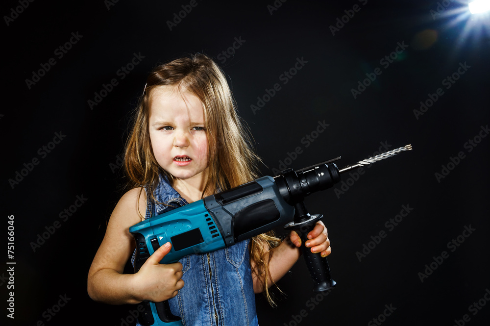 Cute little girl with drilling machine in her hands