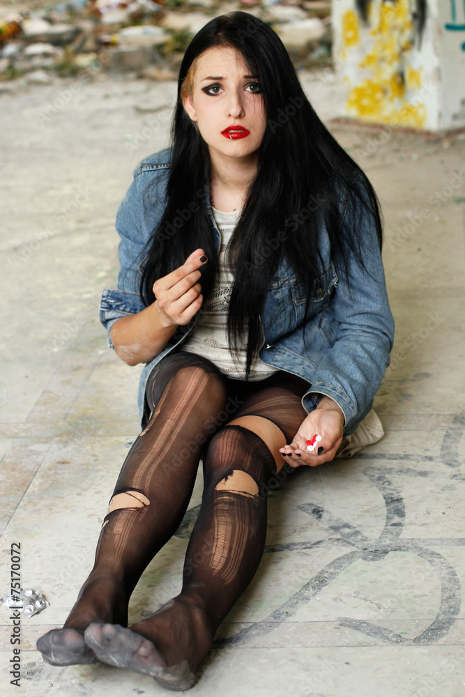 Addict girl in in torn tights and with pills