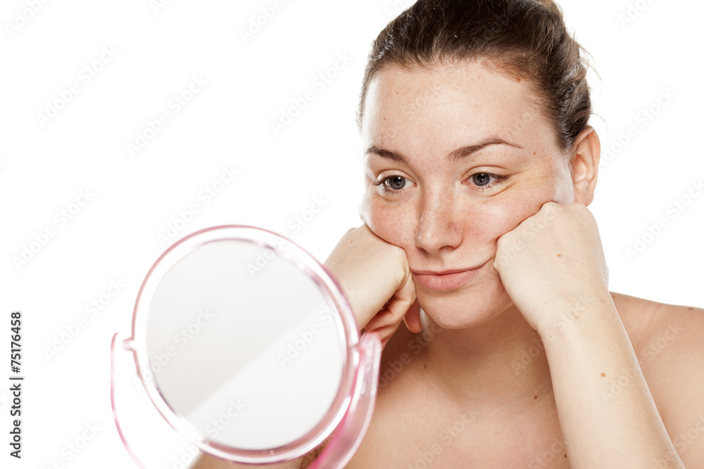 young woman is bored and looking at herself in the mirror young woman is bored and looking at herself in the mirror