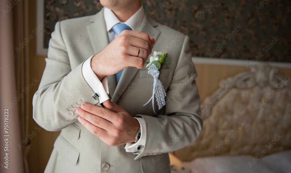 groom in a suit, hands wear cufflinks