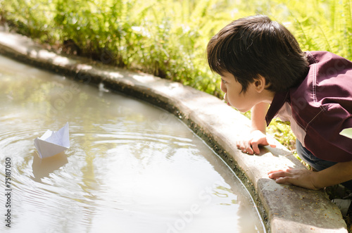 Little boy enjoy blowing paper boat photo