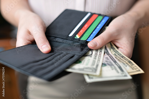 Black purse with money in woman`s hand