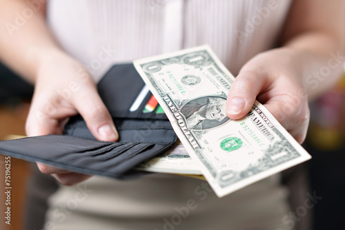 Black purse with money in woman`s hand