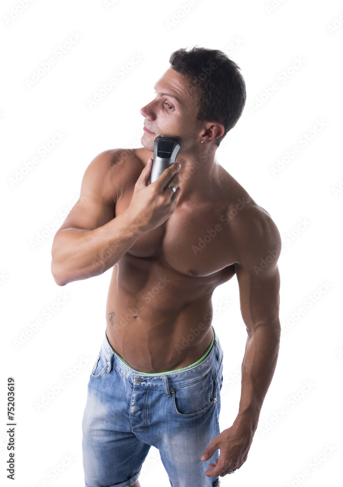 Fototapeta premium Muscular man shirtless using electric shaver, looking away