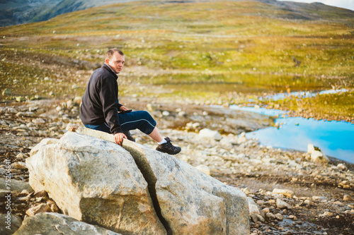 Man Sitting On Stone In Norwegian Mountains