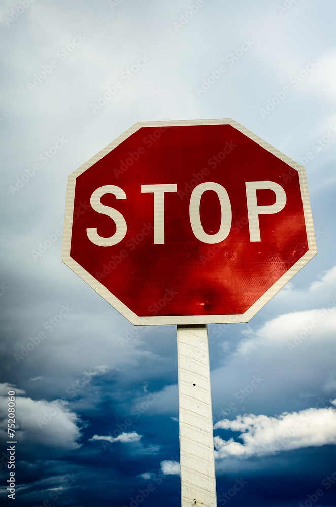 Obraz premium roadside red stop sign on a cloudy background.