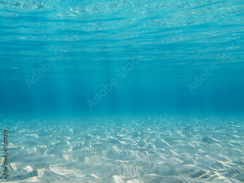 Sandy seabed with sunlight through water surface photo