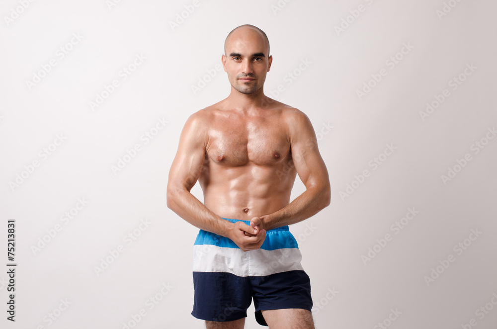 Fototapeta premium Fit bodybuilder showing his body.Muscular topless man in shorts.