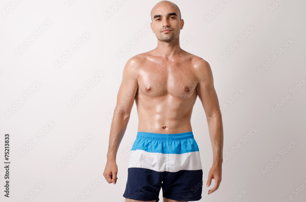 Fototapeta premium Fit bodybuilder showing his body.Muscular topless man in shorts.