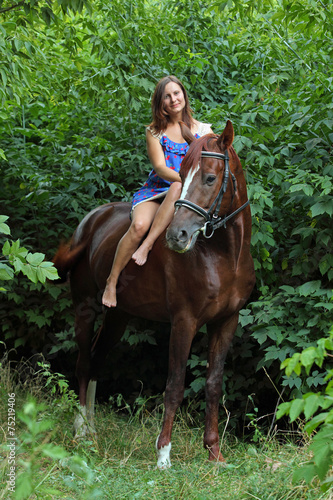 Happy woman posing on top horse in forest
