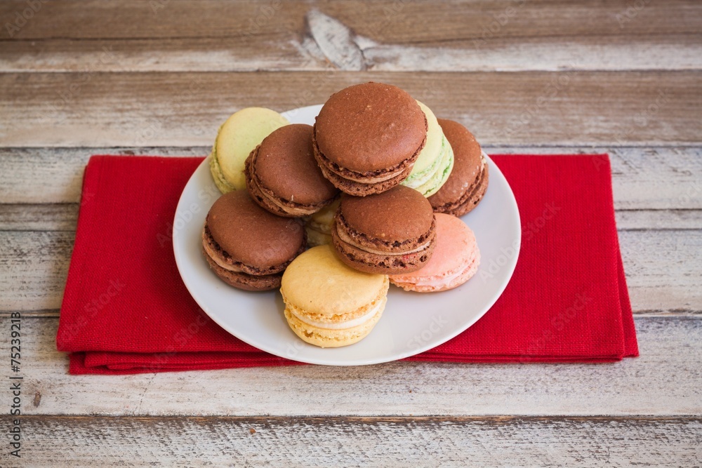 Macarons on plate, on red cloth and wooden table Macarons on plate, on red cloth and wooden table