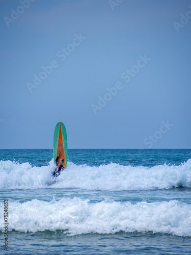 Beautiful young woman surfing in Kuta