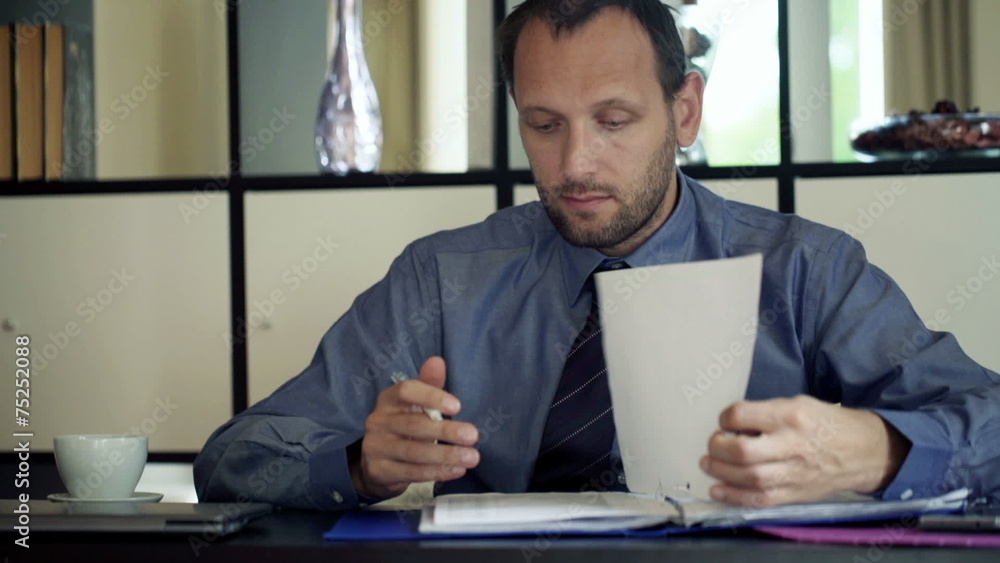 Young, handsome businessman writing notes in documents Young, handsome businessman writing notes in documents