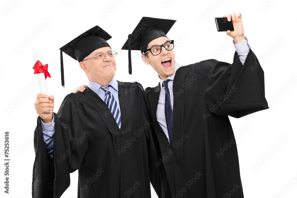 Senior and guy in graduation gowns taking a selfie Senior and guy in graduation gowns taking a selfie