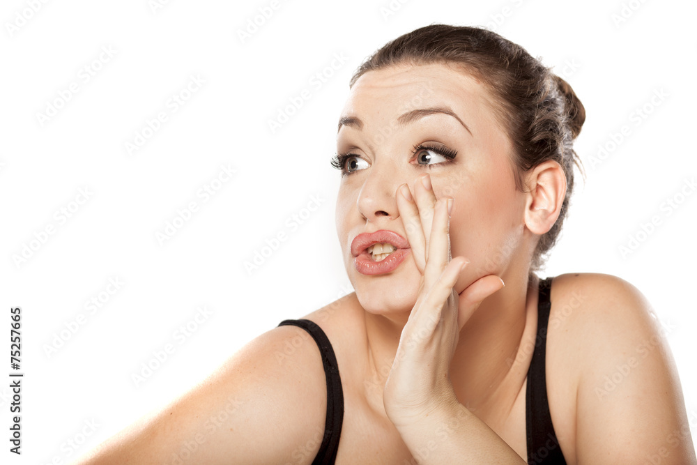 young woman holding hand next to her mouth and whispers young woman holding hand next to her mouth and whispers
