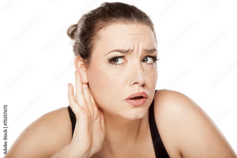 young woman holding a hand behind the ear and listens carefully young woman holding a hand behind the ear and listens carefully
