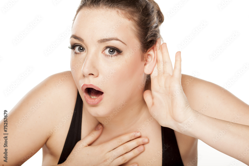 young woman holding a hand behind the ear and listens carefully young woman holding a hand behind the ear and listens carefully