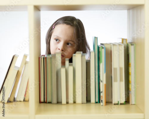 Young girl looking at books on bookshelf