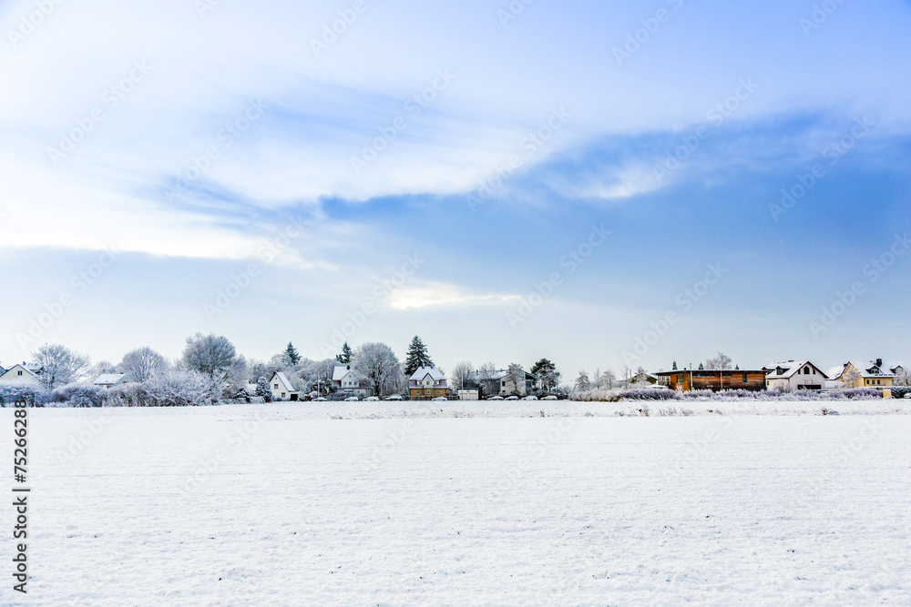 Fototapeta premium snow covered fields with settlement at the horizon in Munich