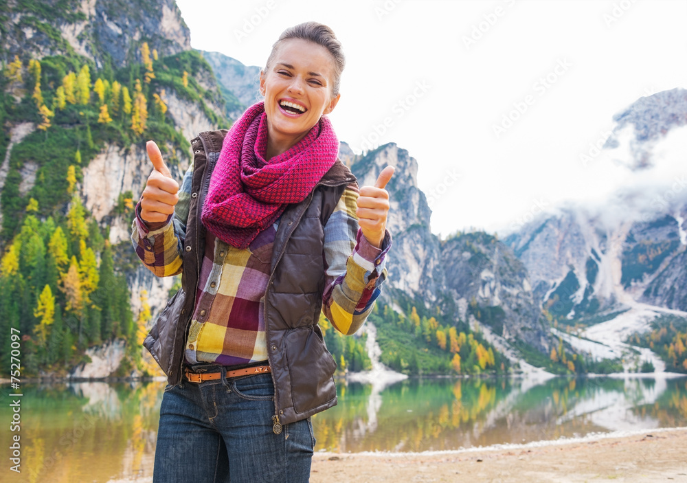 Portrait of smiling young woman on lake braies showing thumbs up