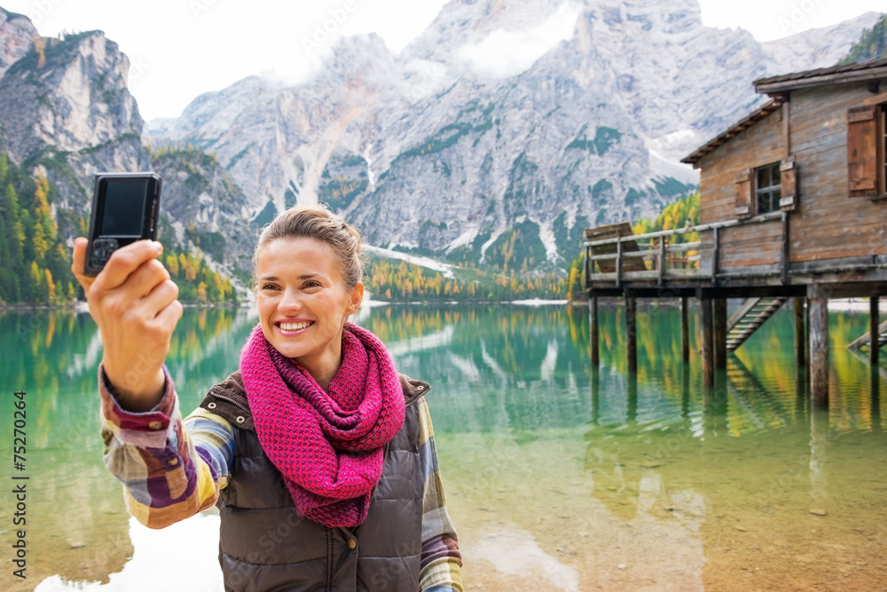 Happy woman making selfie on lake braies in south tyrol, italy