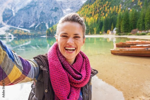 Happy young woman making selfie on lake braies in italy photo