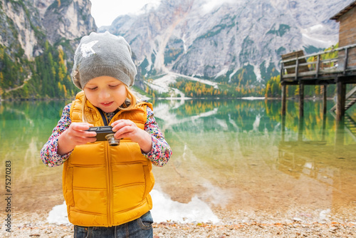 Fototapeta Naklejka Na Ścianę i Meble -  Child checking photos in camera on lake braies in south tyrol