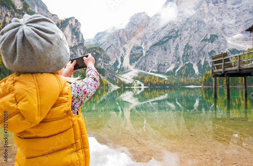 Child taking photo of lake braies in south tyrol, italy