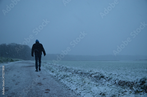 man walking in snowy meadow