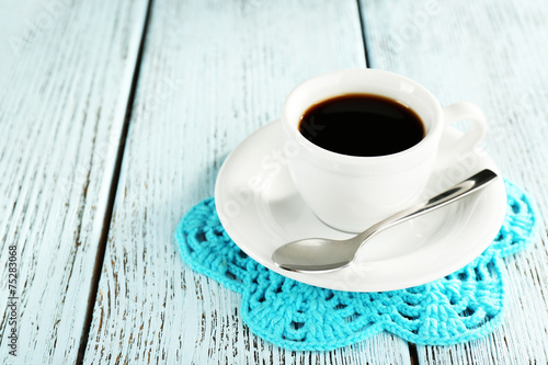 Cup of coffee on lace doily on color wooden background